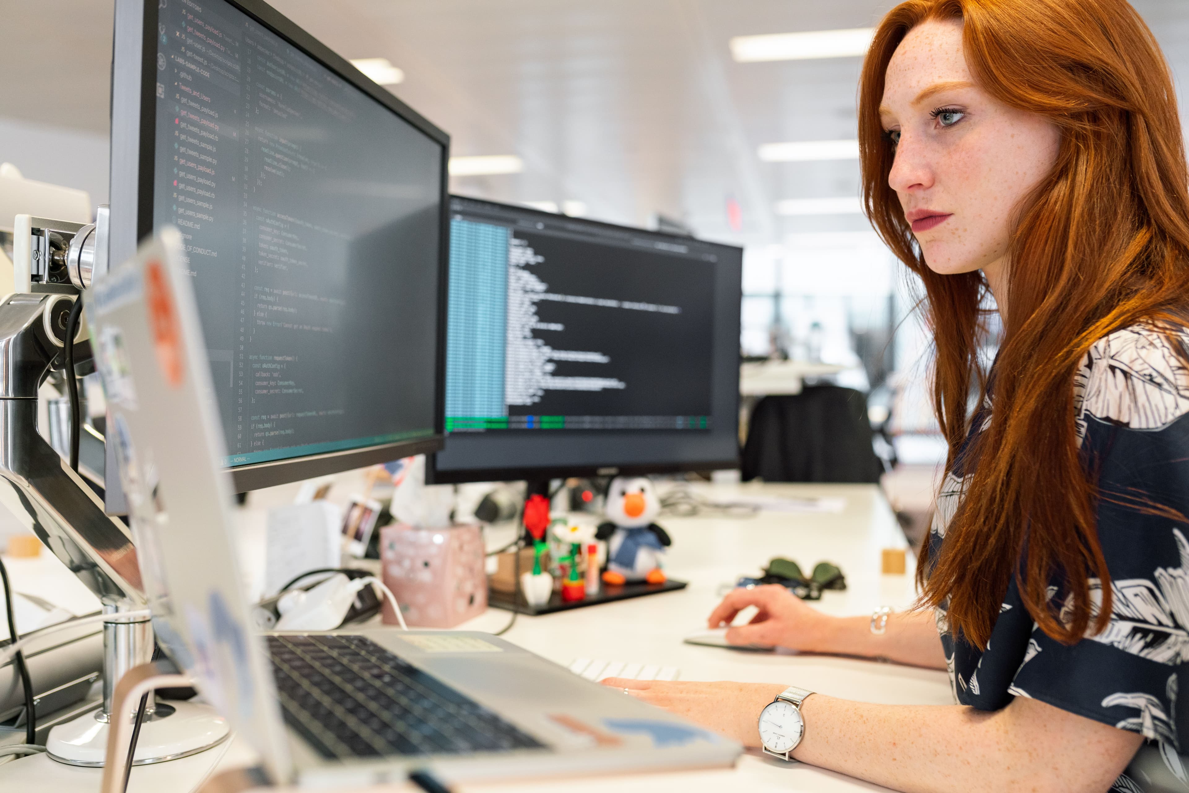 Desenvolvedora programando um sistema web sob medida em dois monitores